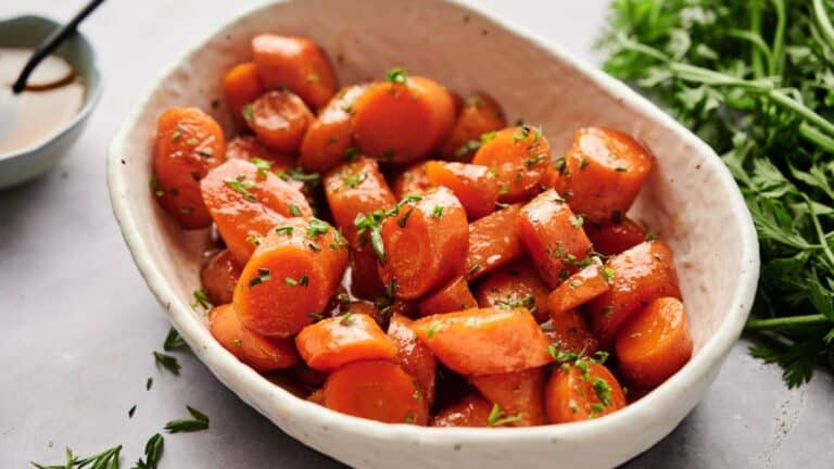 Roasted carrots in a white bowl with herbs.