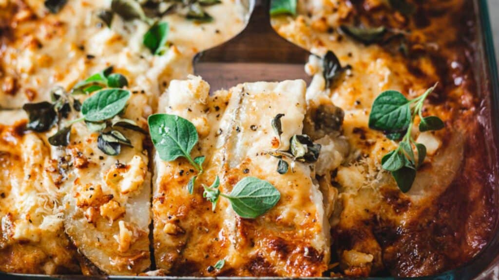 A lasagna with cheese and herbs in a baking dish.