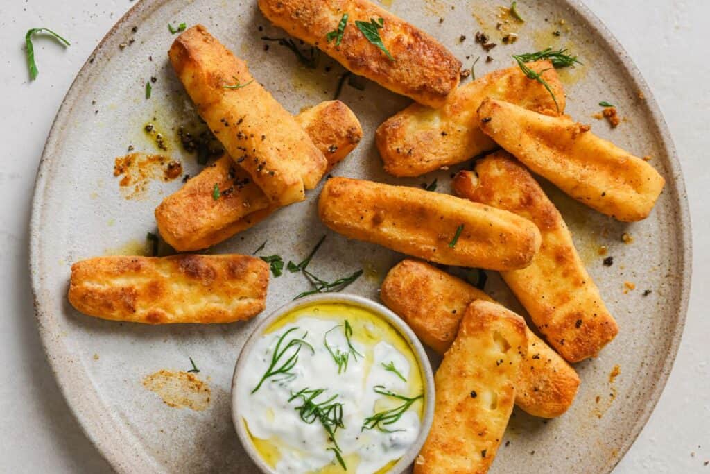 Halloumi fries with dipping sauce on a plate.