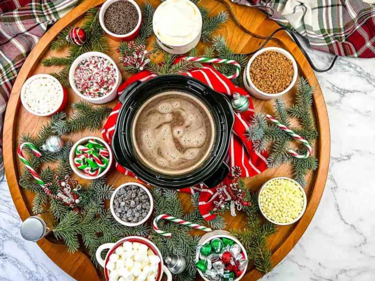 A wooden platter with hot cocoa, candy canes, and marshmallows.