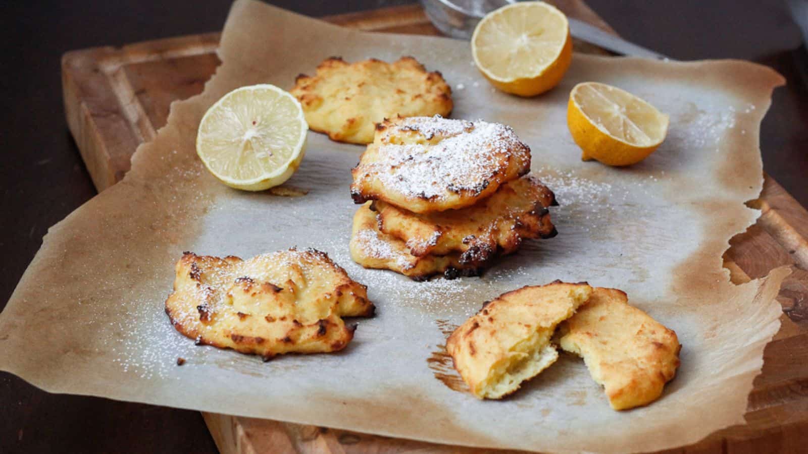 Lemon cookies with powdered sugar on a cutting board.