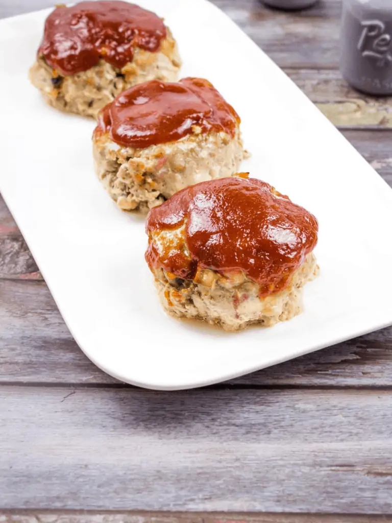 3 Mini Meatloaves in a line on a white plate.