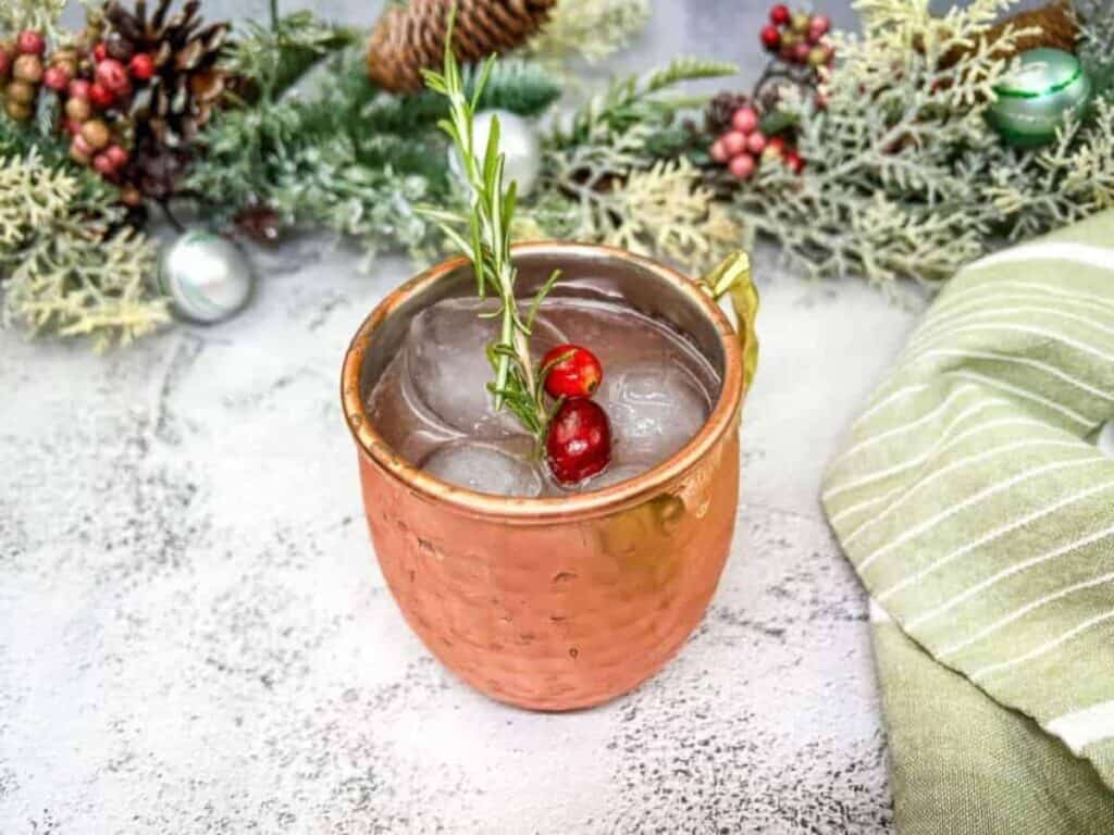 A copper mug with a moscow mule and a sprig of holly.