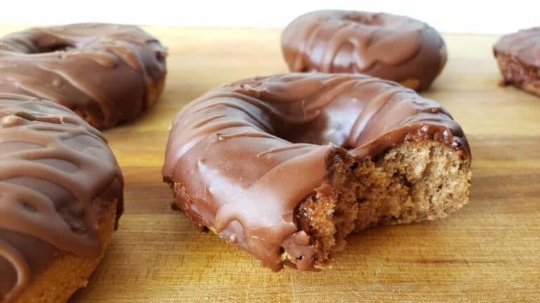 Image shows Mocha donuts on a wooden board with one missing a bite.