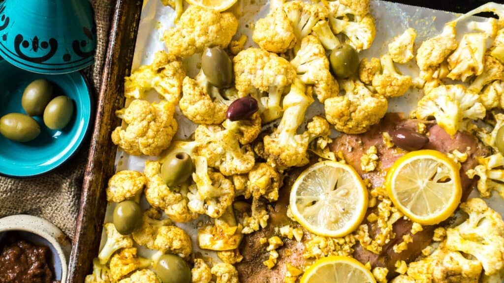 Roasted cauliflower with lemon and olives on a baking sheet.