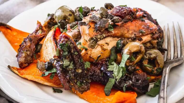 Roasted chicken and sweet potatoes on a plate with a fork.