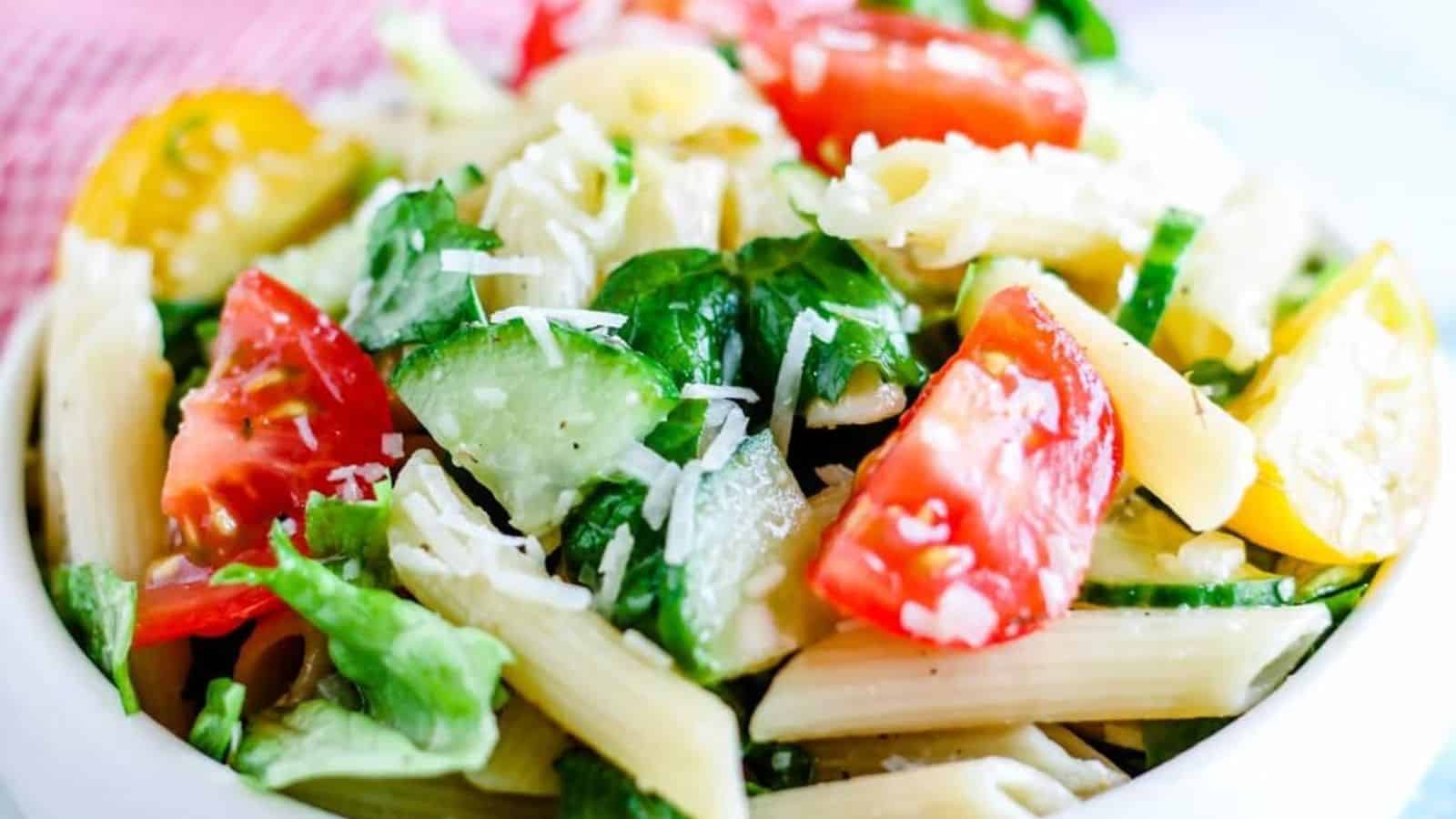 A bowl of pasta salad with fresh greens and veggies.