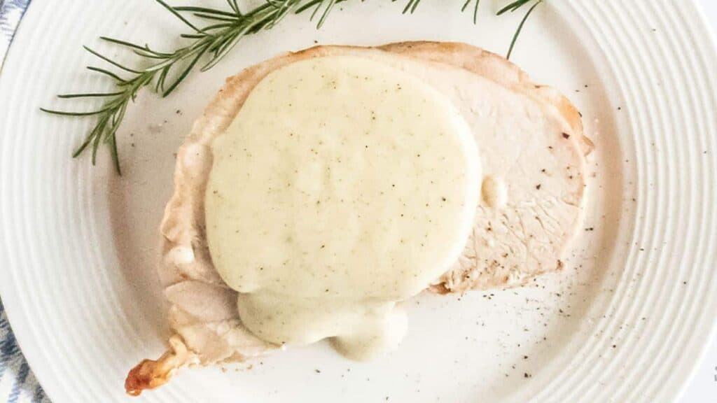 Pepper gravy on pork chop with black pepper garnish and fresh rosemary.