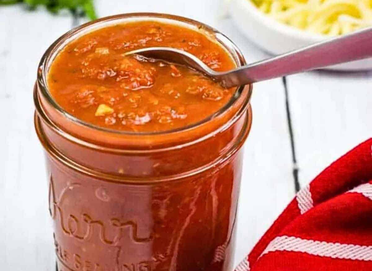 Homemade tomato sauce in a mason jar with a spoon.