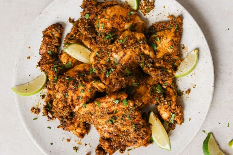 Pollo asado on a white plate with lime wedges.