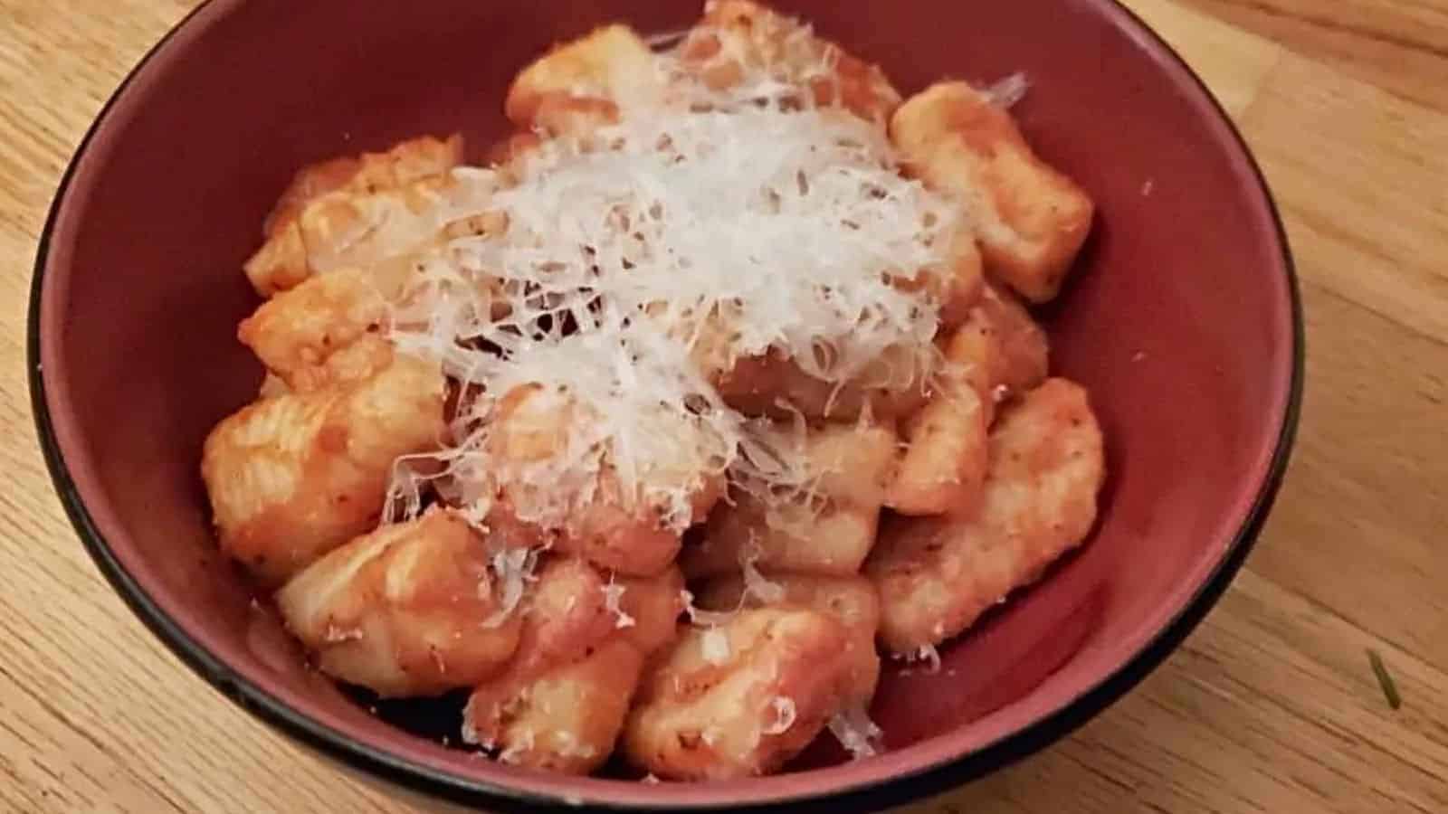Image shows a bowl of Potato Gnocchi with grated cheese atop it.