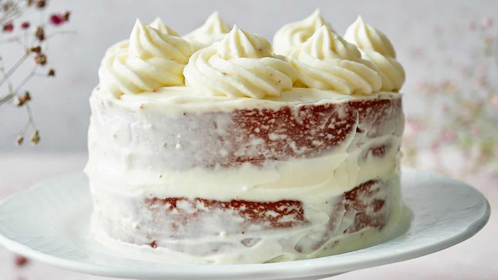 Red Velvet Cake with whipped cream swirls on a cakestand.