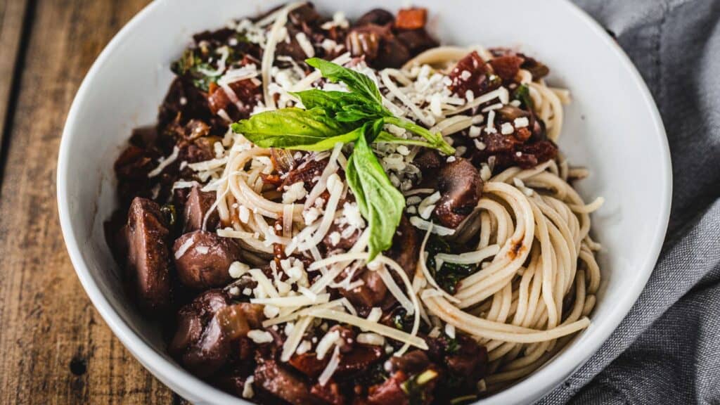 A bowl of spaghetti with meat sauce and basil.