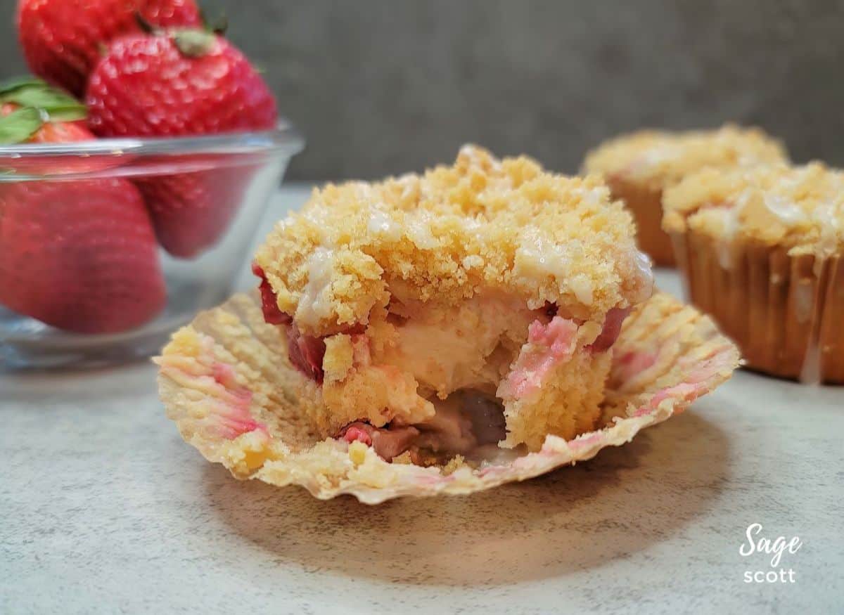 Cream cheese filling inside a strawberry muffin topped with streusel.