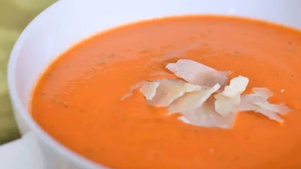 A bowl of tomato soup with parmesan on top.