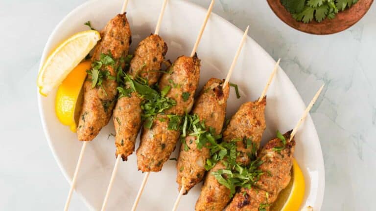 Chicken skewers on skewers with lemon wedges.