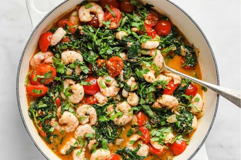 A pan with shrimp, tomatoes and spinach in it.