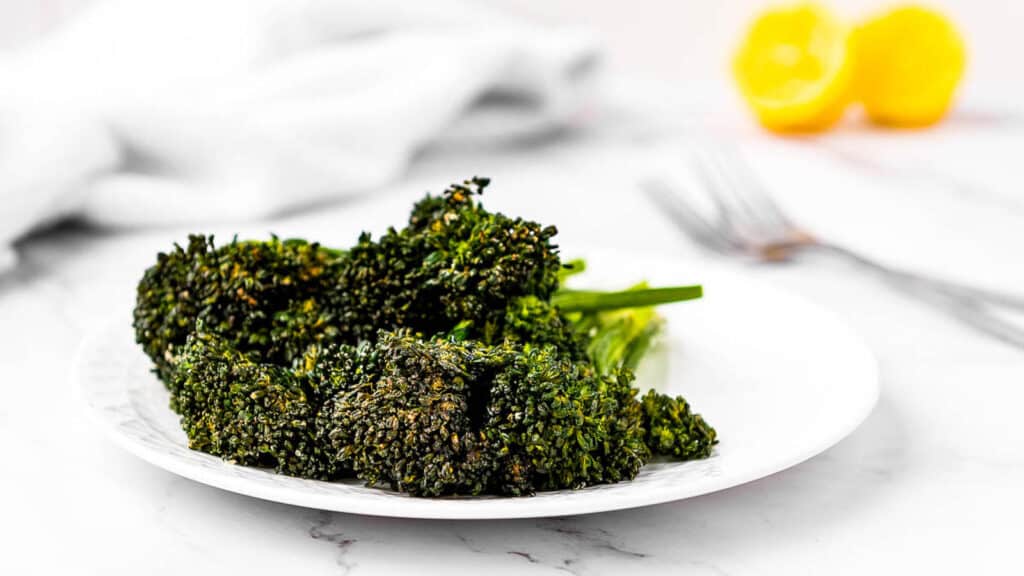 Ingenious air fryer recipe: Broccoli on a white plate with lemon wedges.