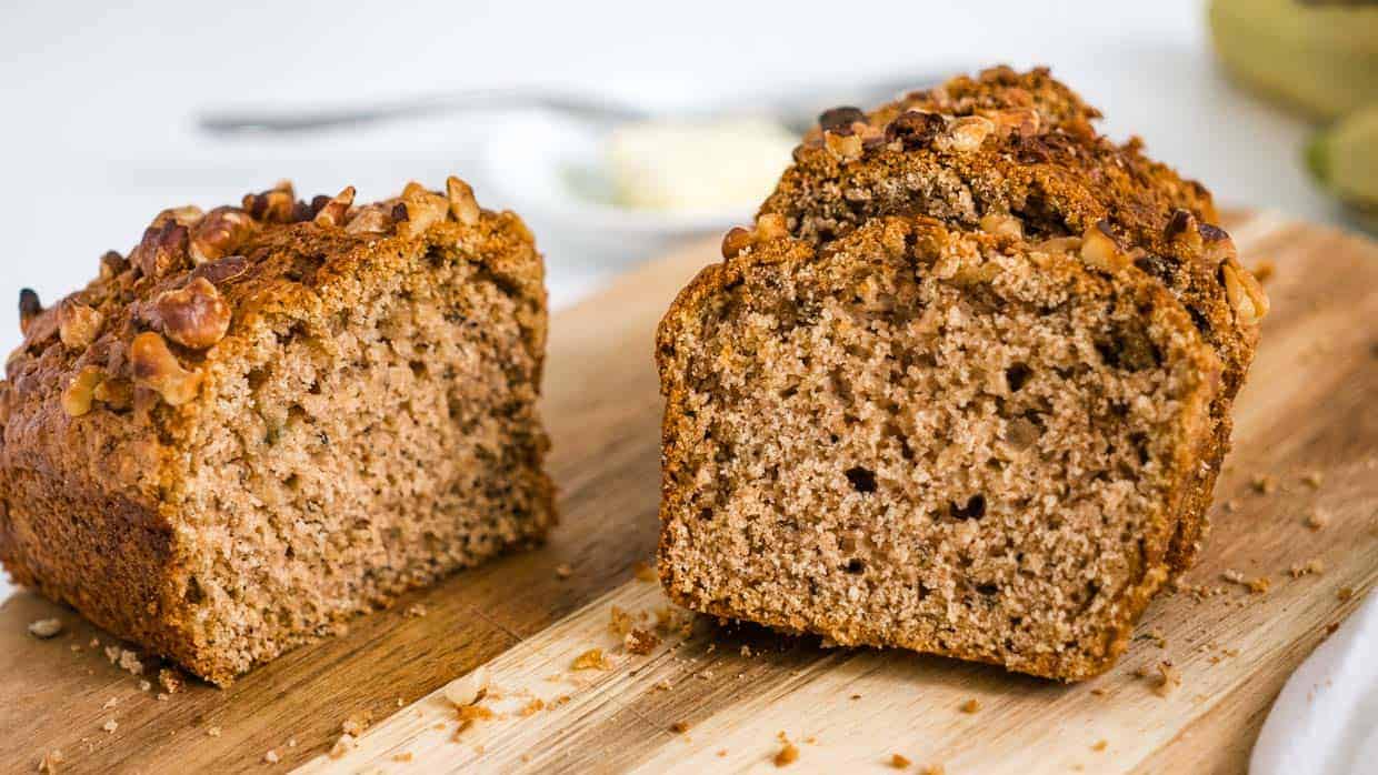 Loaf of air fryer banana bread sliced on a wooden cutting board.