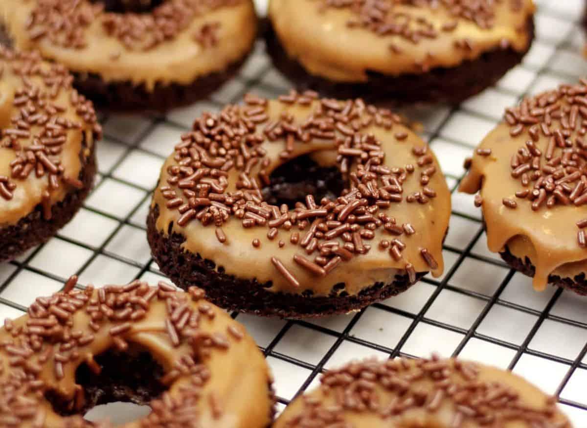 Baked Guinness donuts with chocolate frosting and sprinkles on a cooling rack.