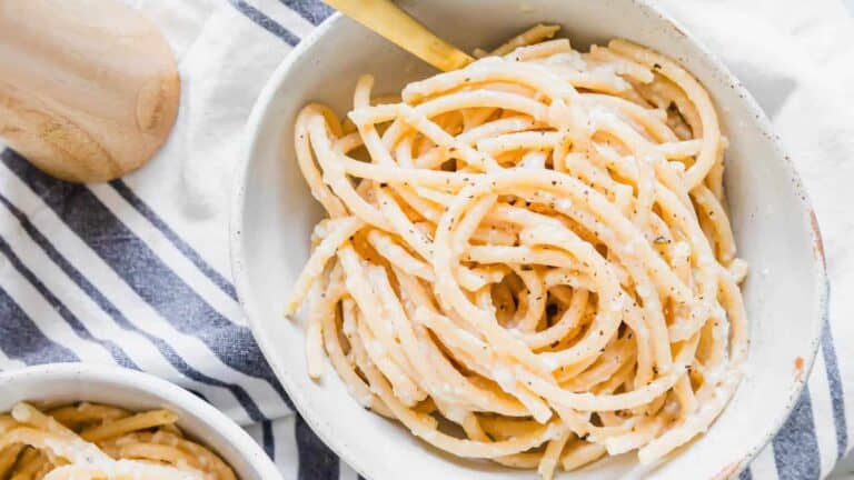 Pasta in a white bowl on a striped towel.