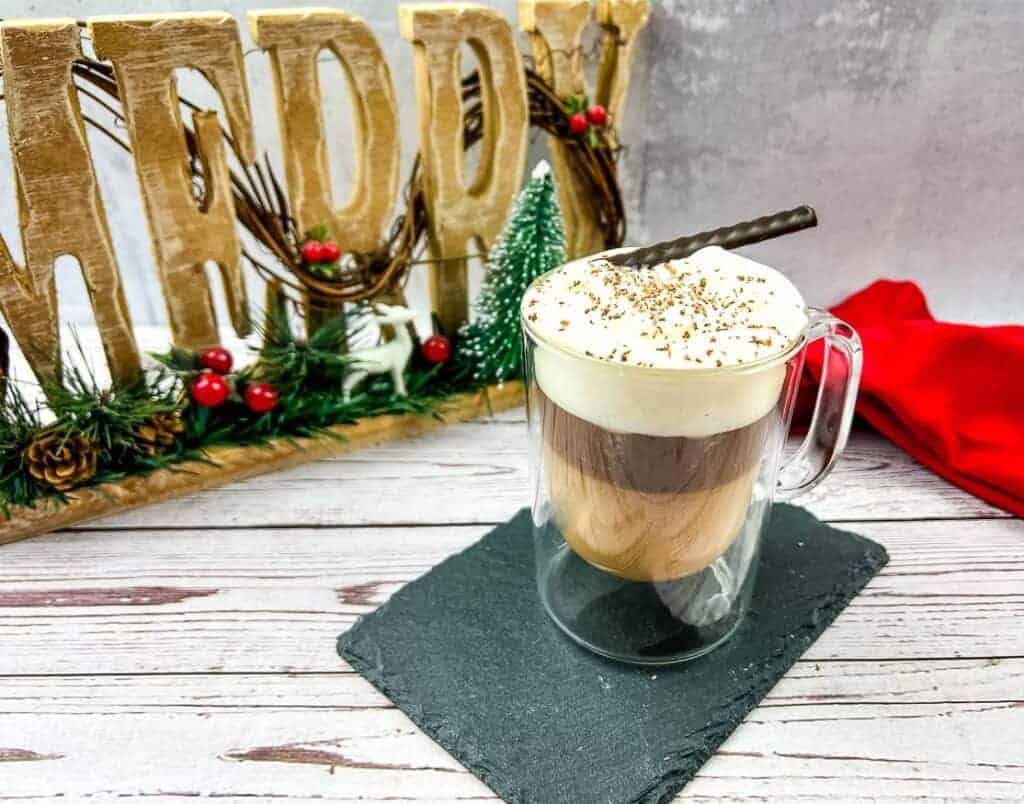 A canadian coffee with a whipped cream and cinnamon sticks.