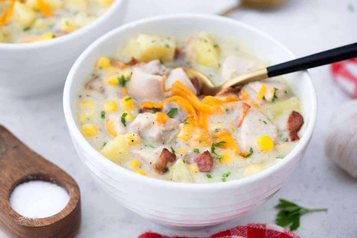 Two bowls of chicken chowder with potatoes and corn.