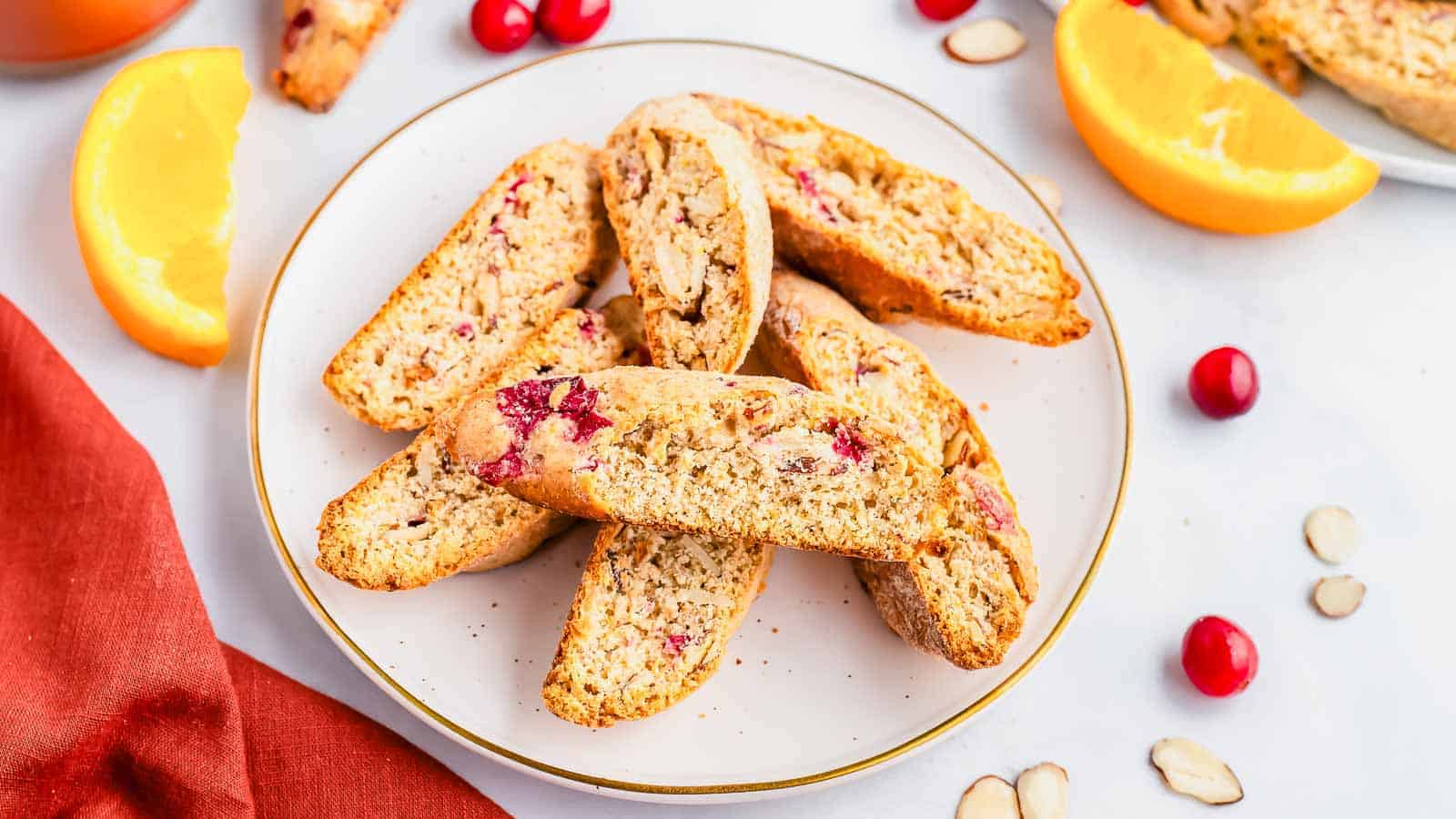 Cranberry biscotti on a plate with orange slices.