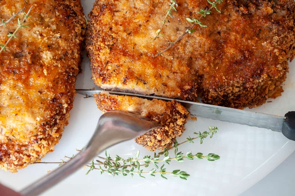 Two pieces of fried chicken on a plate with sprigs of thyme, perfect for winter dinners.