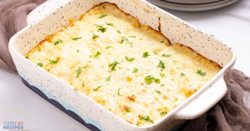 A casserole dish filled with mashed potatoes and parsley.