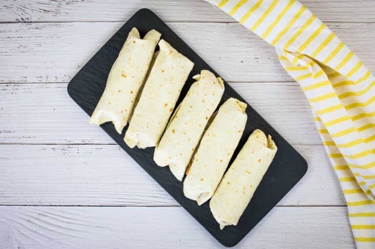 Freezer Breakfast Burritos in a black tray on a wooden table.