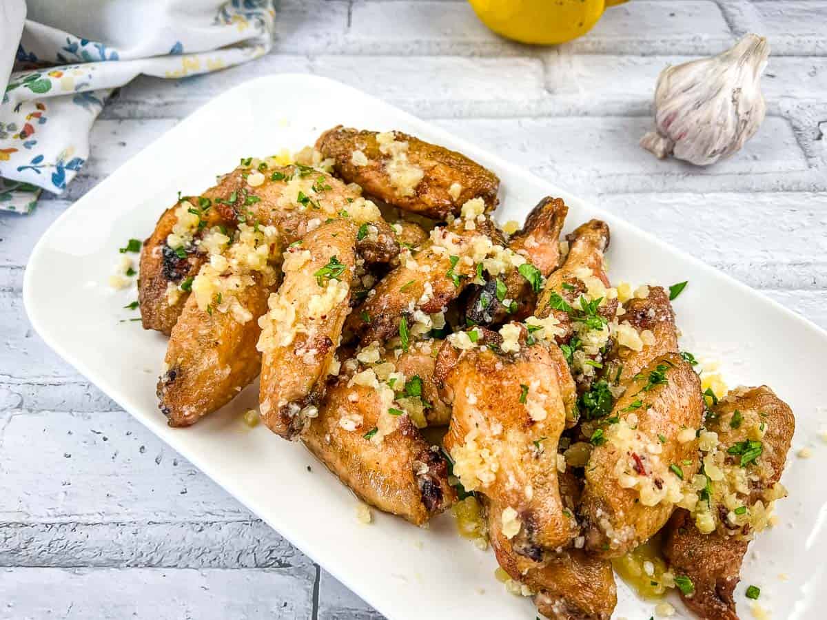 Chicken wings with garlic and Parmesan on a white plate.