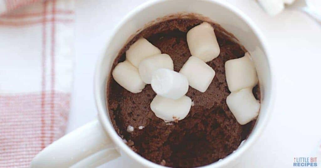 A mug of chocolate pudding with marshmallows on top.