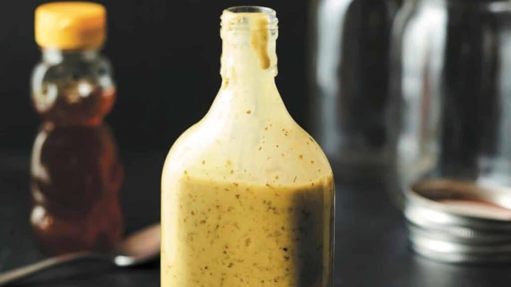 Edible honey mustard dressing in a bottle on a table.