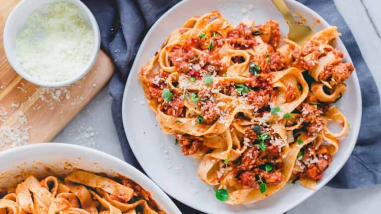 A plate of pasta with meat sauce and parmesan cheese.