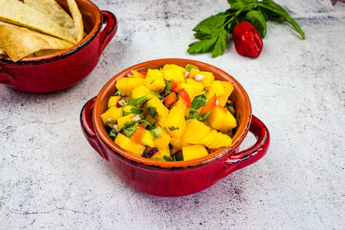 Two bowls of hot mango salsa on a table.