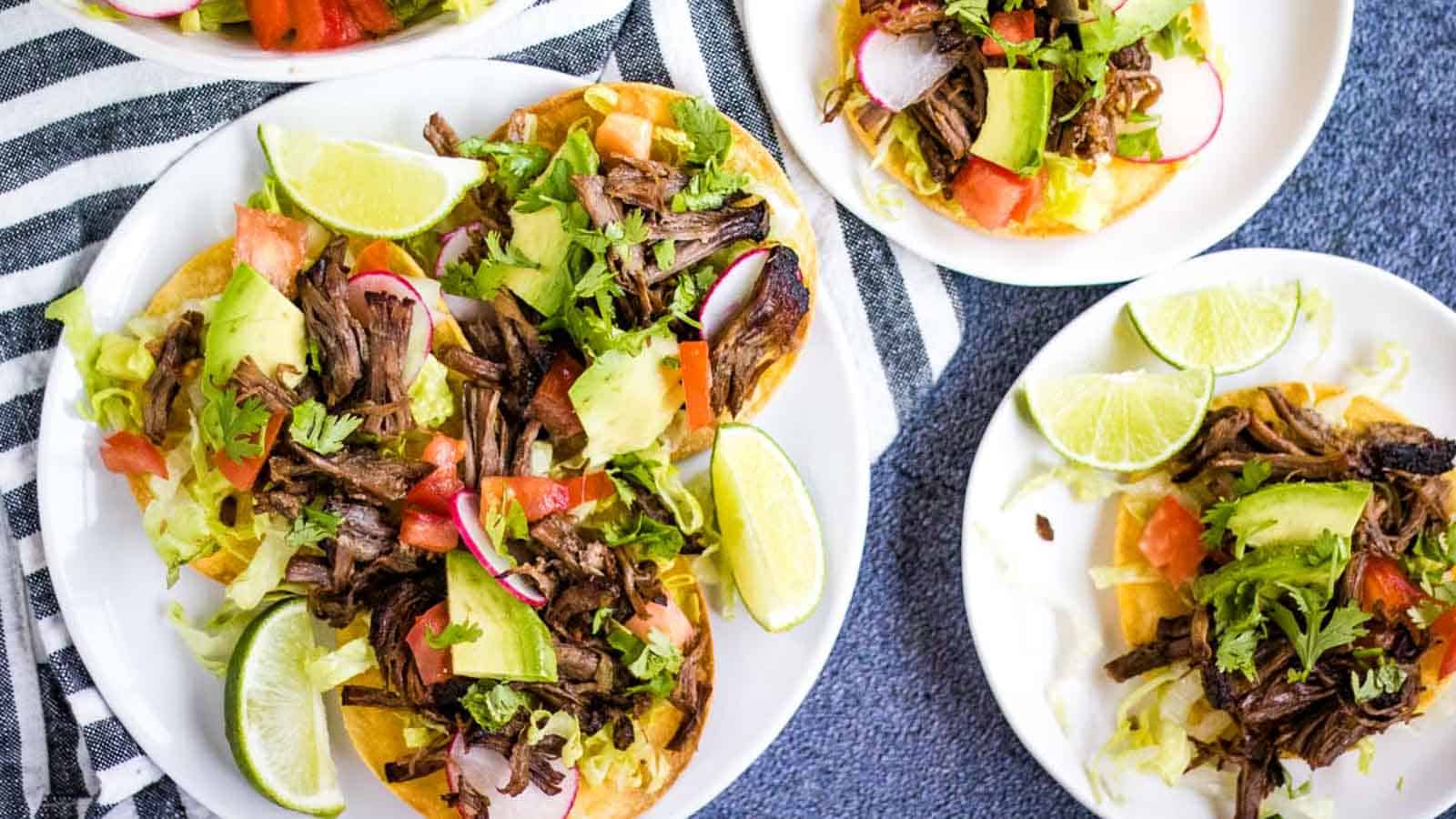 Mexican beef tacos on white plates.