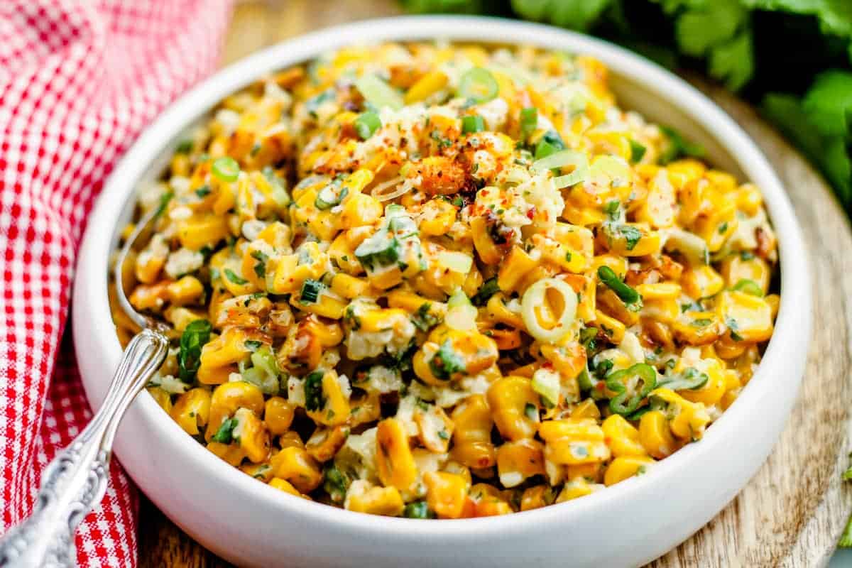 A bowl of Mexican Street Corn with a spoon in it ready to serve.