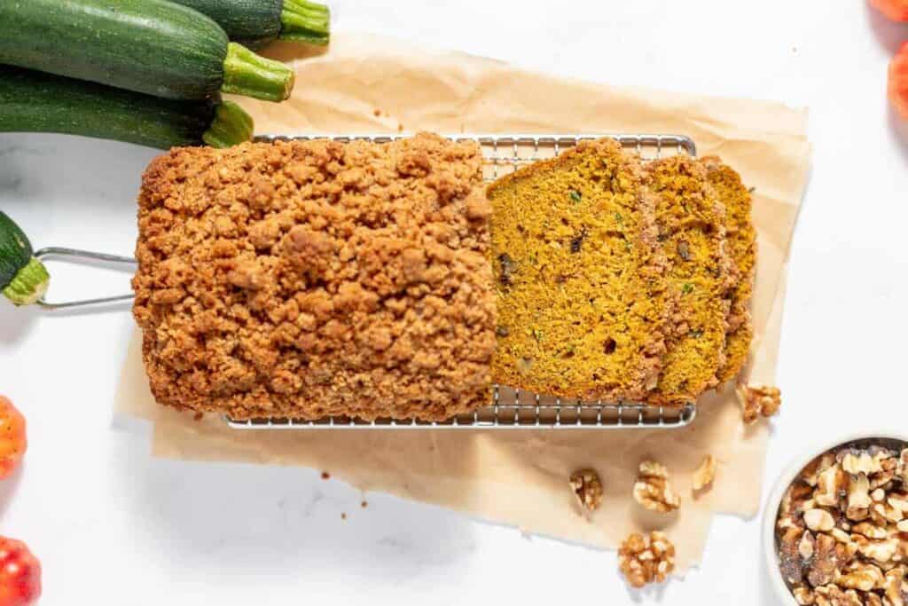 A loaf of pumpkin zucchini bread is sitting on a baking sheet.