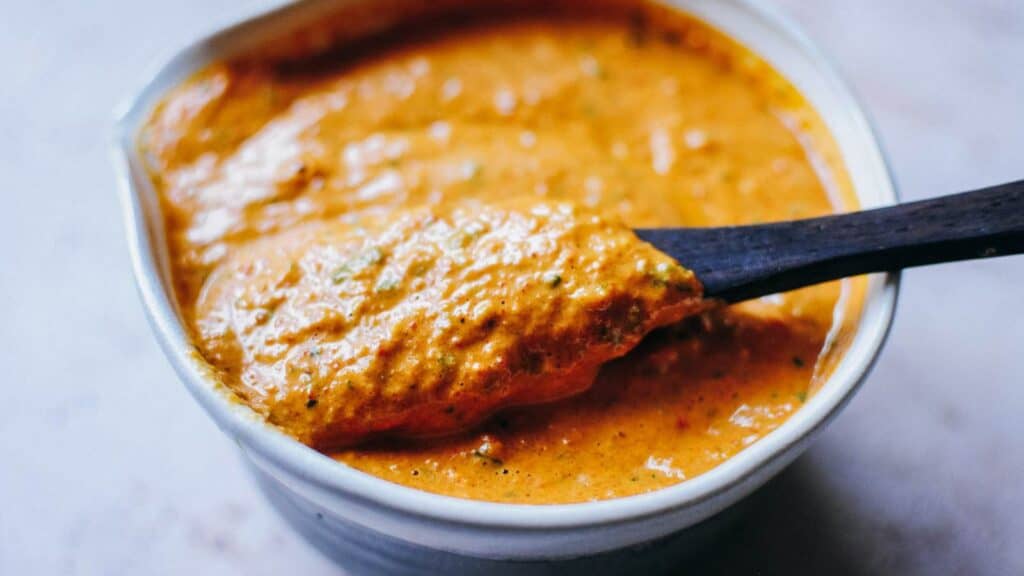 A bowl of romesco sauce with a wooden spoon.