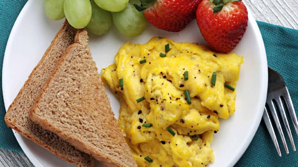 A plate with eggs, toast and fruit.