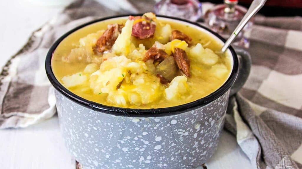 A mug with a bowl of soup and a spoon.