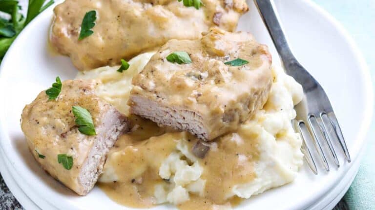 Pork chops with gravy and mashed potatoes on a plate.