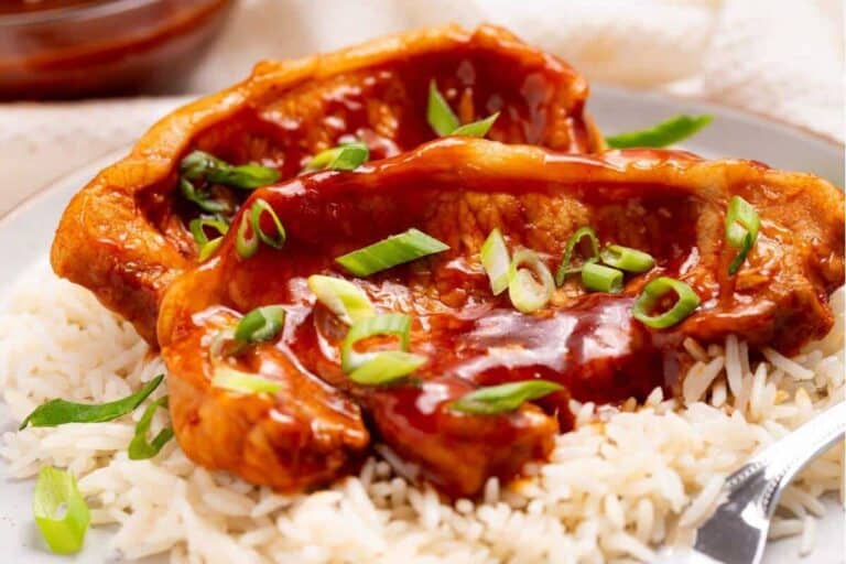 Bbq pork chops on a plate with rice and sauce.