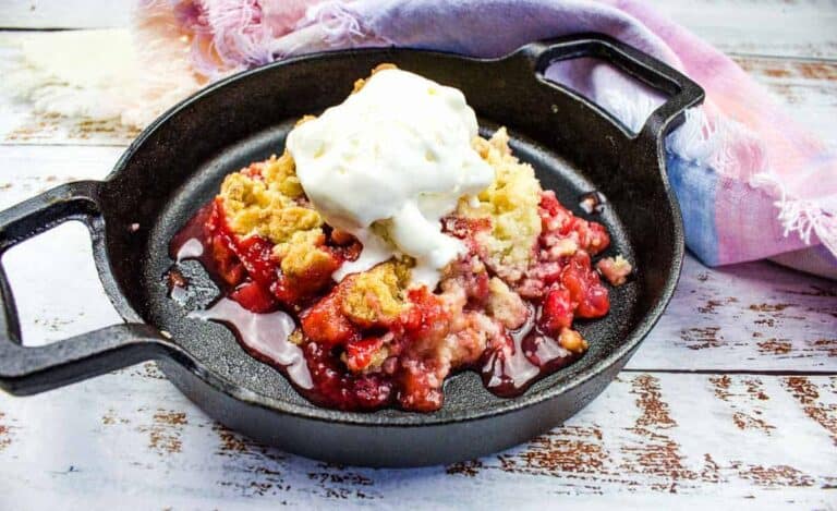 Strawberry cobbler in a skillet with whipped cream.