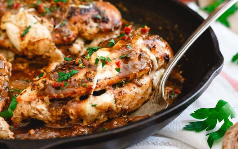 Chicken breasts in a skillet with sauce and herbs.