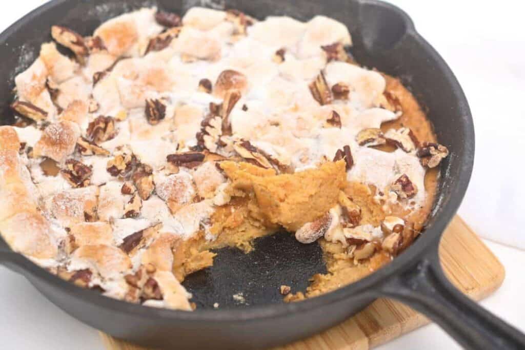 A skillet with a piece of pumpkin pie in it.