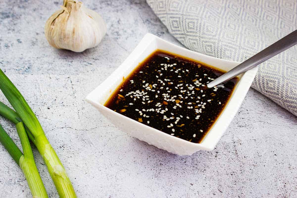Teriyaki sauce in a square dish with green onions nearby.