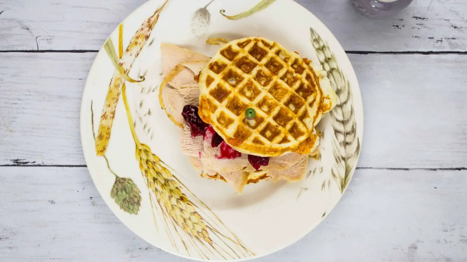 Waffles with turkey and cranberry on a plate.