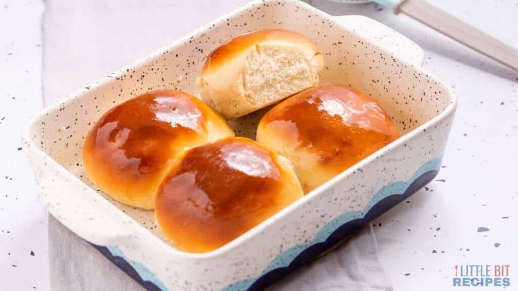 Buns in a blue and white dish with a spoon.